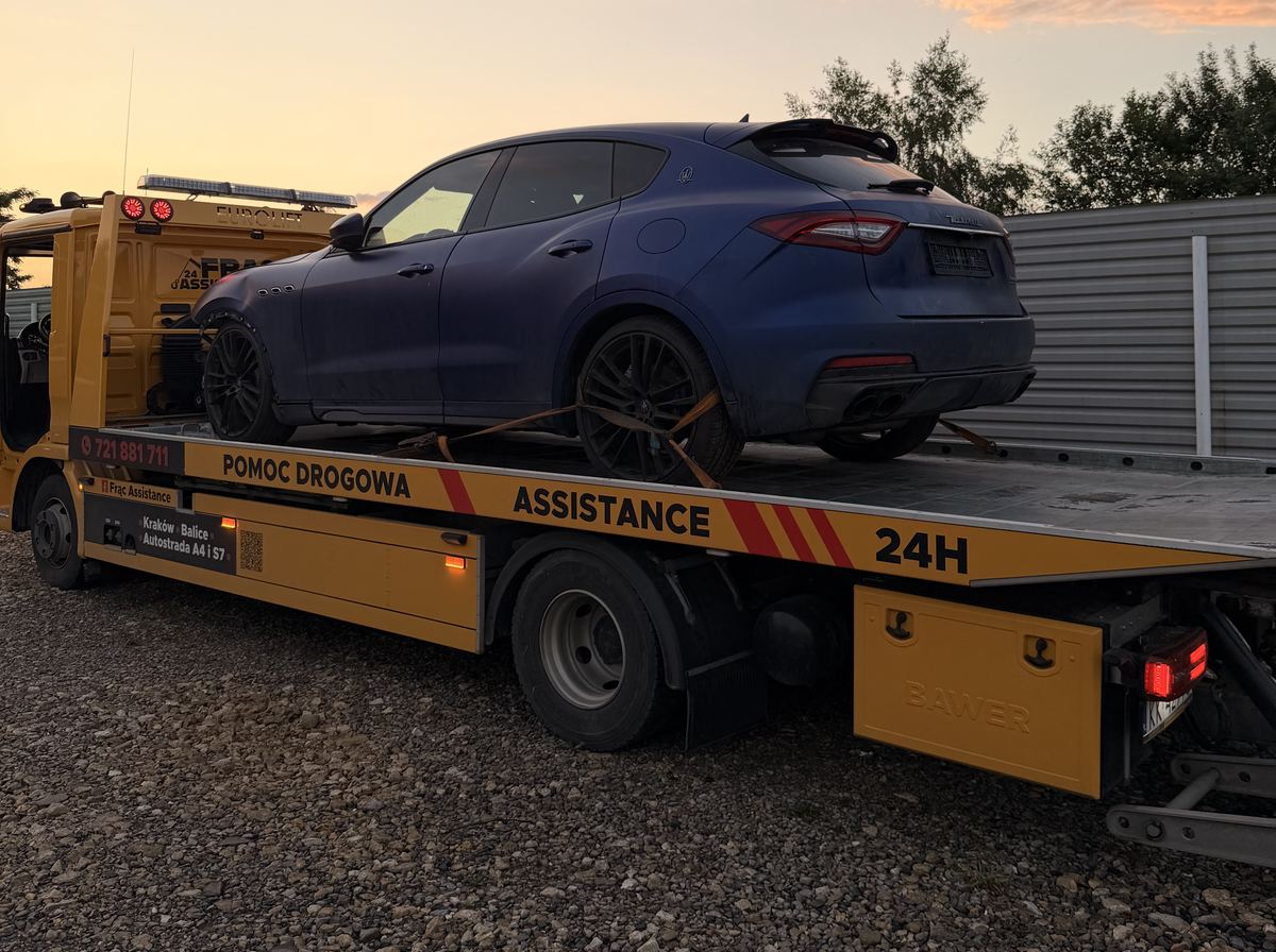 Holowanie samochodu osobowego Maserati Levante na lawecie o zachodzie słońca w okolicy Balic
